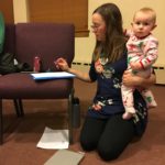 a woman holding a baby while sitting on a chair.