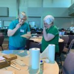 a couple of women standing next to each other at a table.