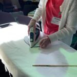 a woman ironing a sheet of paper with an iron.