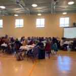 a group of people sitting at tables in a large room.