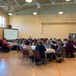 a group of people sitting at tables in a large room.