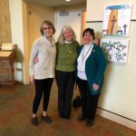 three women standing next to each other in a room.