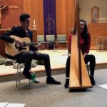 a man and a woman playing guitars in a church.