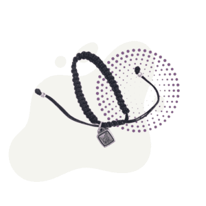 The Caring Cord Bracelet with Sheep Charm, featuring a black braided cord and a small silver sheep charm, is displayed against a white background adorned with purple dotted accents.